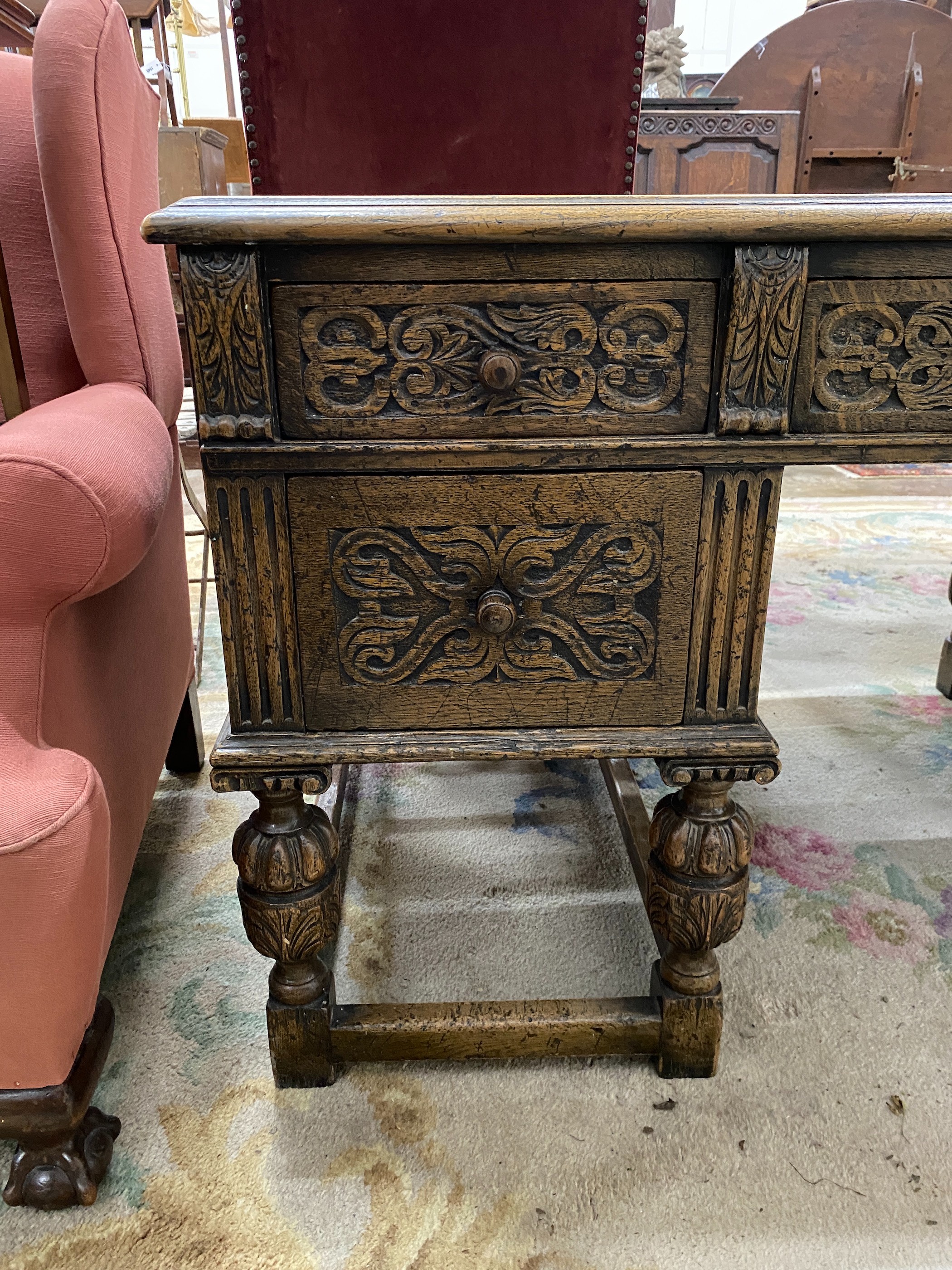 A 1920's Jacobean revival carved oak five drawer kneehole desk, length 144cm, depth 83cm, height 75cm